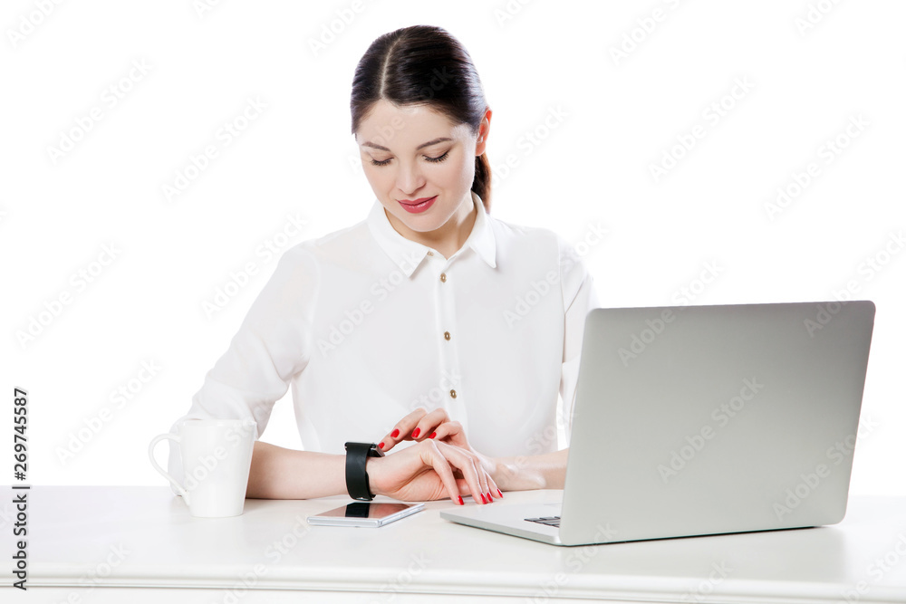 Portrait of happy attractive brunette businesswoman in white shirt sitting looking and touching her smartwatch display, reading something and smiling. indoor studio shot, isolated in white background. Portrait of happy attractive brunette businesswoman in white shirt sitting looking and touching her smartwatch display, reading something and smiling. indoor studio shot, isolated in white background.