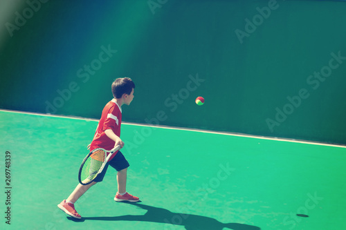Little tennis player on a blurred green background © allasimacheva