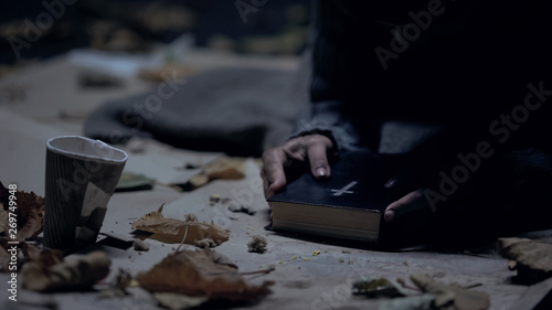 Miserable vagabond holding bible and praying to God, strong belief, faith