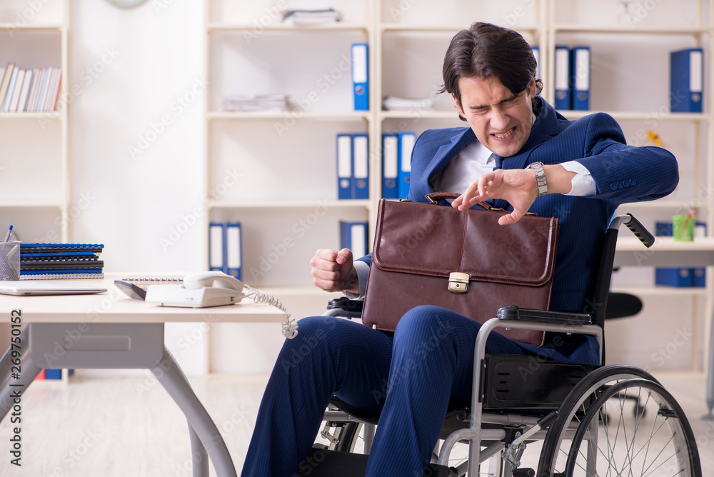 Young male employee in wheelchair working in the office 