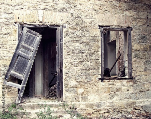 Old damaged window and broken door of an abandoned house.