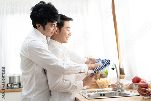 Obraz na plátně Young Asain happy male gay couple is washing dishes while doing cleaning  at kitchen