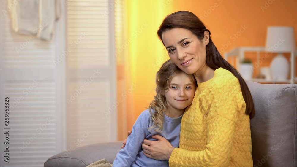 Beautiful smiling lady hugging happy girl, family looking to camera, parenthood Beautiful smiling lady hugging happy girl, family looking to camera, parenthood