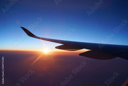 red sunlight spreading on aerial cloud and land below airplane wing