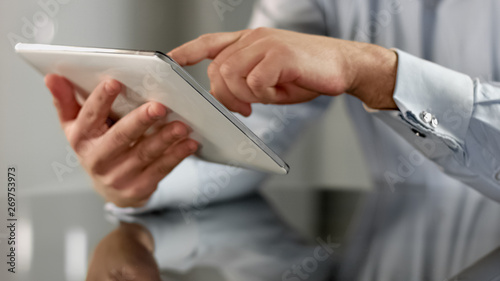 Businessman hands scrolling news application on tablet, touchscreen device
