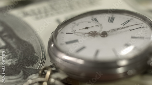 Pocket watch lying on one hundred dollar bill time is money, finance and banking