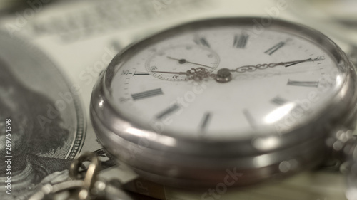 Old pocket watch on dollar bill, money working, time running out, world economy