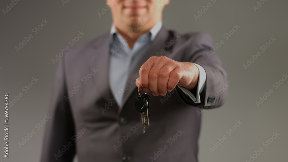 Man in suit holding keys, renting car or apartment, real estate agent profession