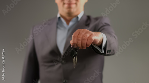 Man in suit holding keys, renting car or apartment, real estate agent profession