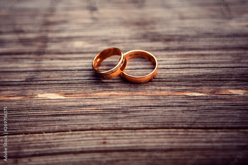 wedding rings. jewelery in white and yellow gold. Wedding ring on the wooden texture. wooden stub wedding rings. jewelery in white and yellow gold. Wedding ring on the wooden texture. wooden stub