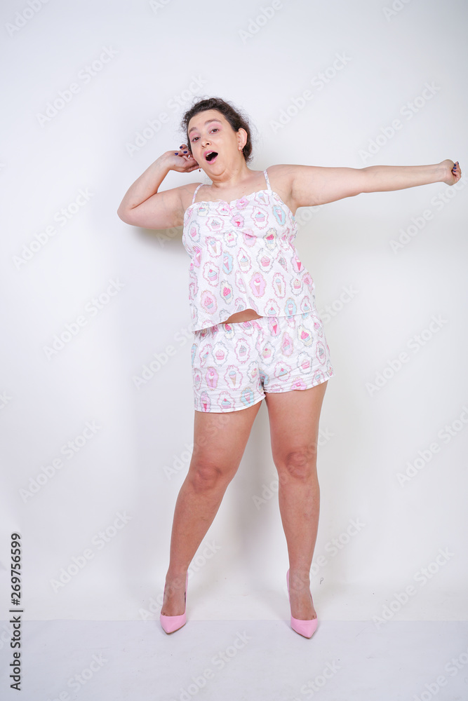 chubby woman in funny pajamas stands and stretchintg on a white background in the Studio chubby woman in funny pajamas stands and stretchintg on a white background in the Studio