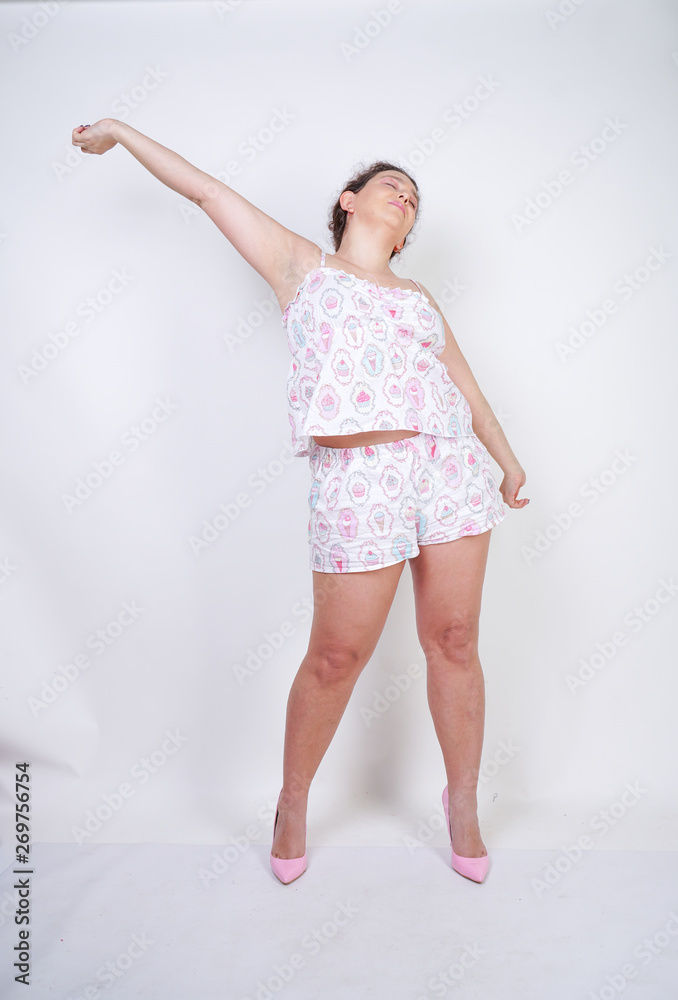 chubby woman in funny pajamas stands and stretchintg on a white background in the Studio chubby woman in funny pajamas stands and stretchintg on a white background in the Studio