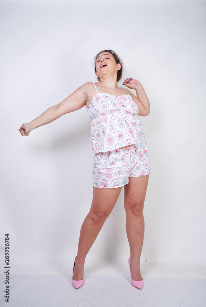 chubby woman in funny pajamas stands and stretchintg on a white background in the Studio chubby woman in funny pajamas stands and stretchintg on a white background in the Studio