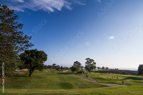 Blue skies over a beautiful Southern California golf course with lush green grass and pine trees