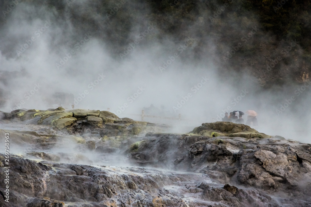 A walk through a geothermal park in Rotorua, New Zealand with tourists in the fog