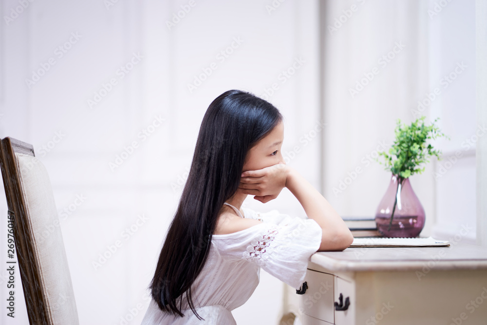sad little asian girl sits at desk thinking sad little asian girl sits at desk thinking