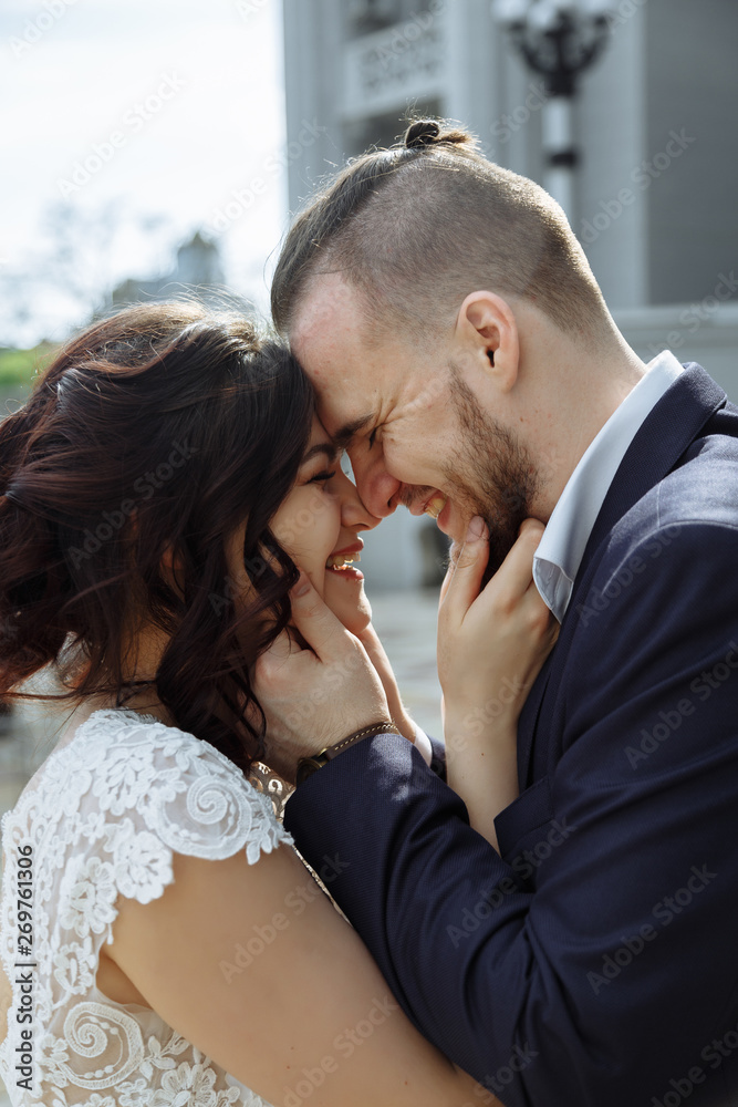 Young beautiful stylish pair of newlyweds hugs each other and stay face to face with smile on stairs. Young beautiful stylish pair of newlyweds hugs each other and stay face to face with smile on stairs.