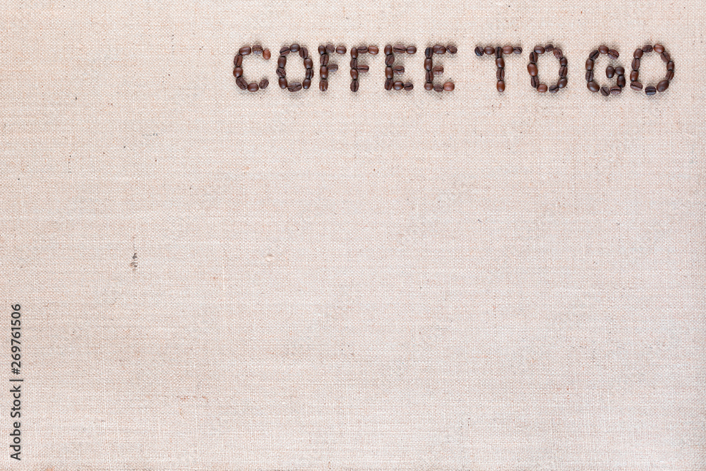 Coffee to go written with coffee beans on linen canvas, arranged top right