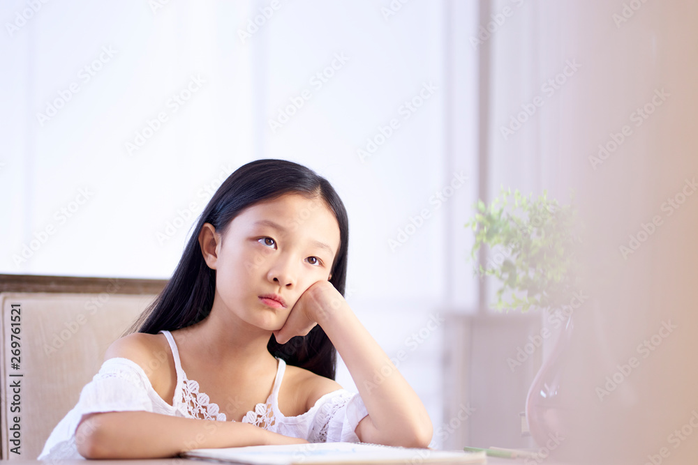 sad little asian girl sits at desk thinking sad little asian girl sits at desk thinking