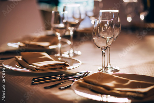 served table with white tablecloth. white plates, wine glass, fork, knife