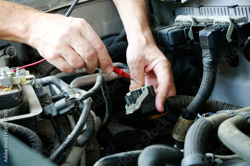 Auto technician troubleshooting electrical problems in car/truck engine