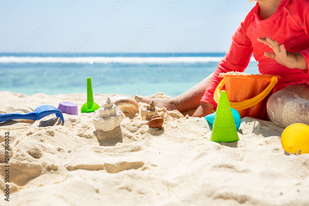 Toddler Girl Playing With Colorful Toys And Seashells On Sand Toddler Girl Playing With Colorful Toys And Seashells On Sand
