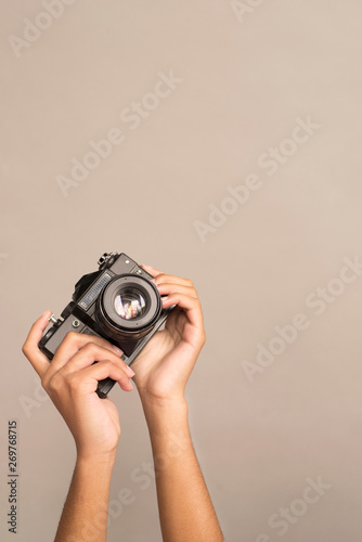 hands holding a camera on a gray background. analog film camera