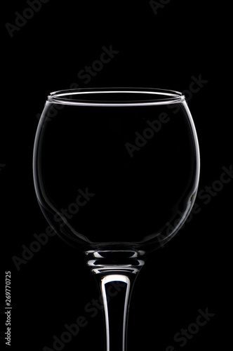 фотографія Wineglass consecrated by silhouette light with reflection on a black background
