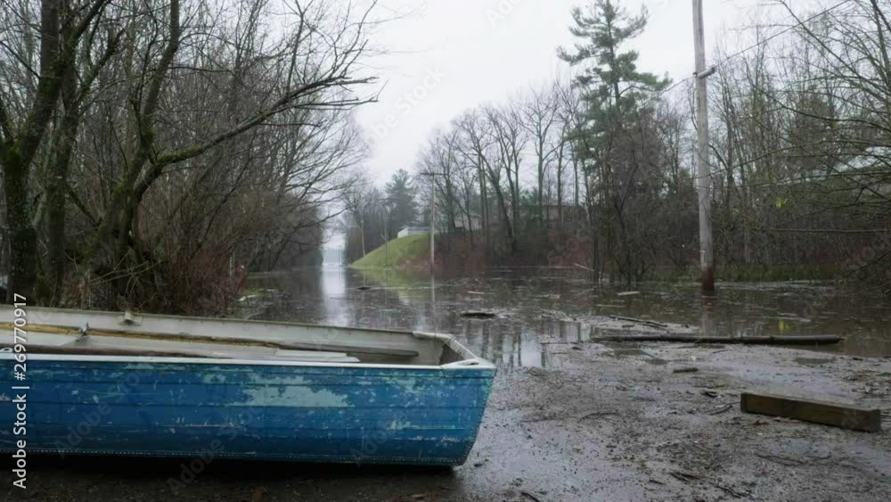Establishing wide shot of flood waters covering an entire road with a boat in the foreground