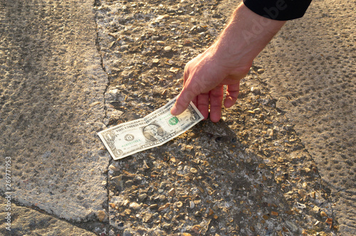 The lucky man is finding the money in the street on the floor. The fortunate person has found a dollar. A chance for a bet in a casino. 