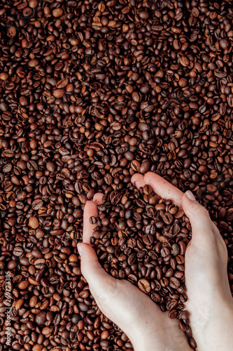 Coffee beans in man palms in form of a heart on coffee background