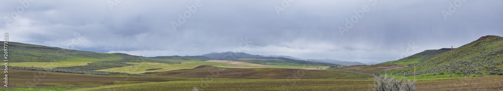 Landscape stormy panorama view from the border of Utah and Idaho from Interstate 84, I-84, view of rural farming with sheep and cow grazing land in the Rocky Mountains. United States.