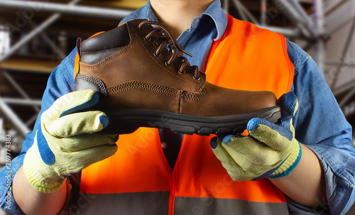 Fotografía Worker in orange jacket outfit holding boot.