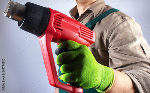 Worker in green overall outfit with heat gun tool. photo