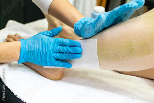 Cold wax legs depilation with hair removal paper strips. Body, health care © stivog