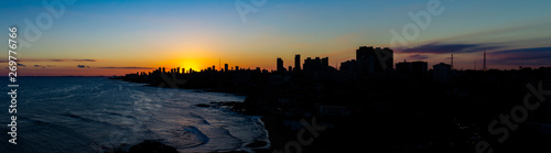 Beautiful sunset in the city of Salvador de Bahia in the northeast of Brazil. Huge buildings cover the sunset. The sea reflects light with silver tones. © Horacio Selva