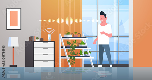 man using smart speaker voice recognition activated digital assistants concept auto watering system modern living room interior flat horizontal full length