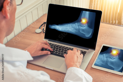 Foto Doctor watching a laptop and a digital tablet with x-ray of pain relief on the a