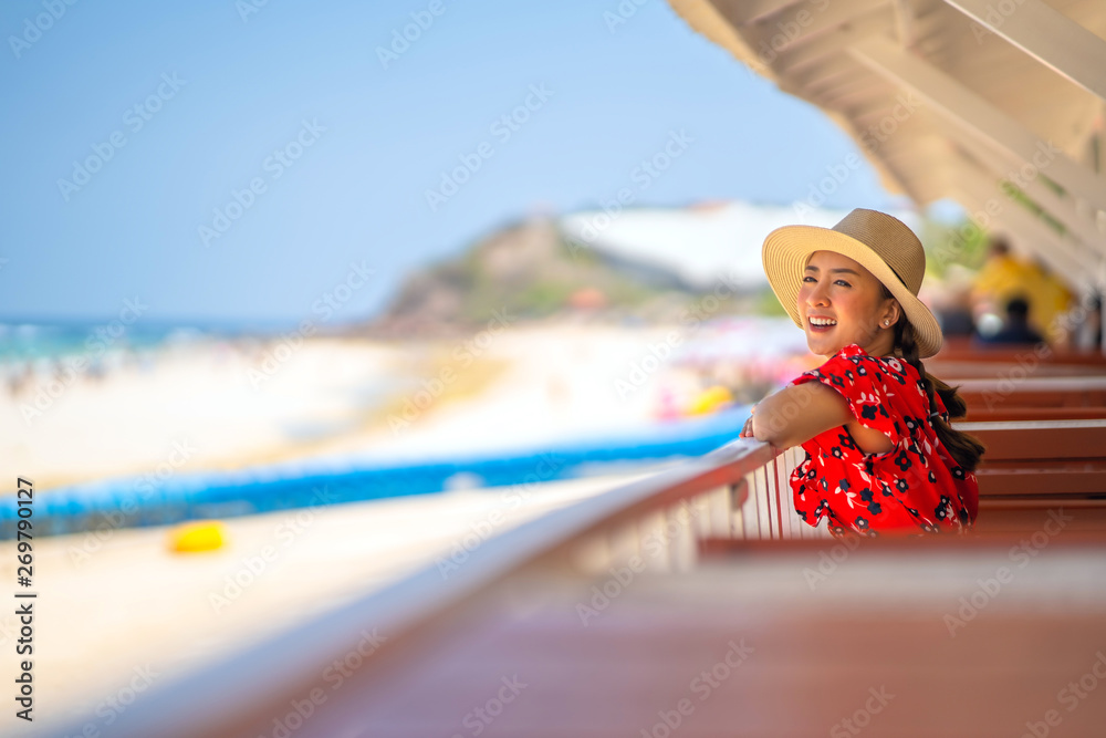 portrait Young woman in a red dress and sunglasses and hat posing on the tropical beautiful beach Travel and Vacation. Freedom and relax Concept.