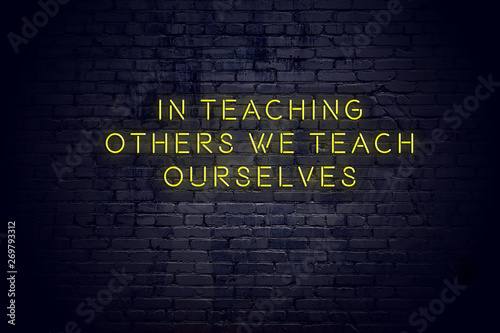 Neon sign with positive wise motivational quote against brick wall 