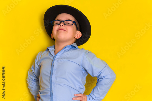 portrait of proud beautiful little boy in hat and shirt isolated on yellow background photo