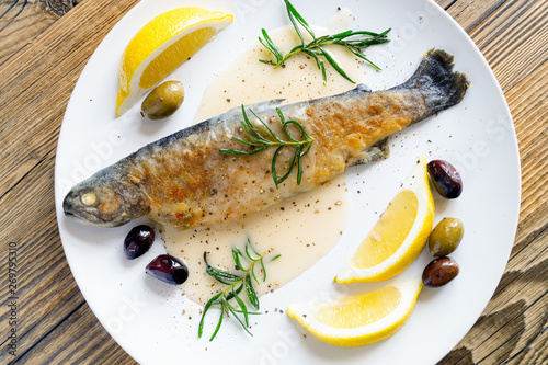baked flour coated trout with gravy on white wine, served with fried rosemary, lemon slices, and olives