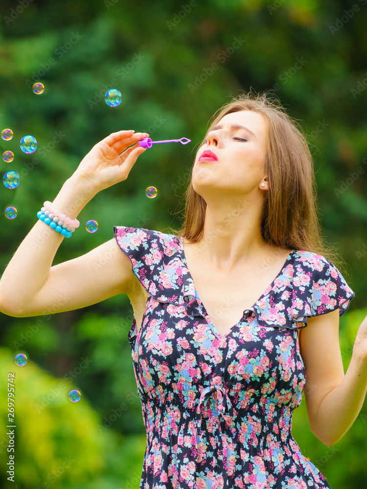 Woman blowing soap bubbles, having fun