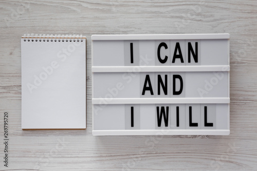 'I can and I will' words on a modern board, blank notepad over white wooden table, top view. Overhead, from above. Flat lay. © Liudmyla