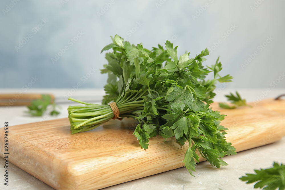 Wooden board with fresh green parsley on table, closeup Wooden board with fresh green parsley on table, closeup