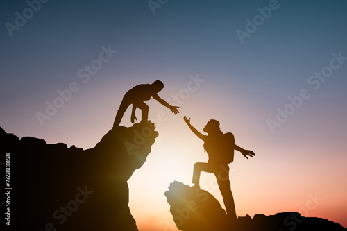 help and improve concept, silhouette people helping other hiker climbing rock and mountain photo