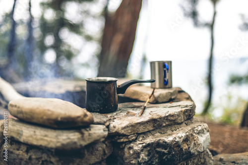 Making coffee in cezve on the fireplace when camping or hiking. coffee on campfire