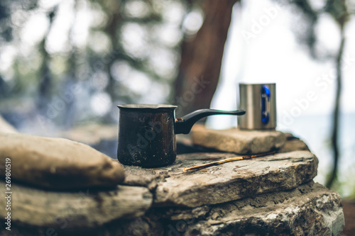 Making coffee in cezve on the fireplace when camping or hiking. coffee on campfire