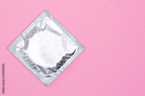 Silver condom on a pink background with copyspace