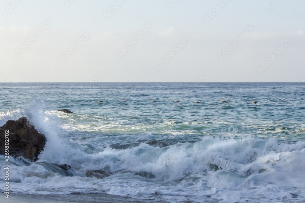splashing wave breaking on rock, with swirling foam from breaking wave and returning backwash